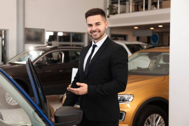 Galerideki yeni arabanın yanındaki genç satıcı.