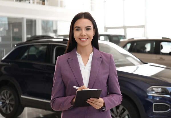 Mladá Prodavačka Schránkou Moderním Autosalonu — Stock fotografie