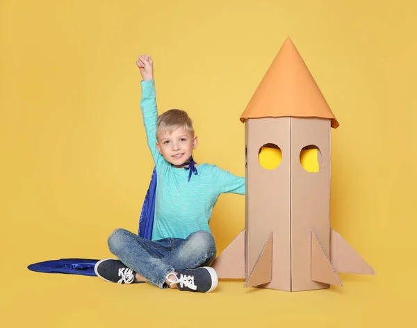 Kleines Kind Umhang Spielt Mit Rakete Aus Pappschachtel Auf Gelbem — Stockfoto