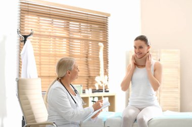 Kadın ortopedist klinikte boynu yaralı bir hastayı muayene ediyor.
