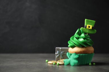 Madalyalı kek ve hediye paketi gri masada, mesaj için yer var. Aziz Patrick Günü kutlaması