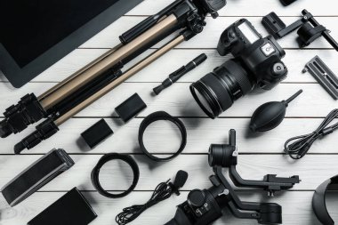 Beyaz ahşap masa üzerinde kamera ve video üretim ekipmanları ile düz kompozisyon yatıyordu