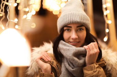 Açık havada festival ışıklarının yanında güzel bir genç kadın. Kış tatili