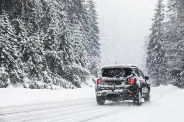 Ormanın yakınındaki karlı yolda modern bir araba. Kış tatili