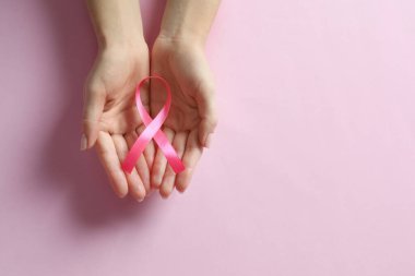 Renkli arka planda pembe kurdele tutan kadın, yazı için yeri olan üst manzara. Göğüs kanseri farkındalığı