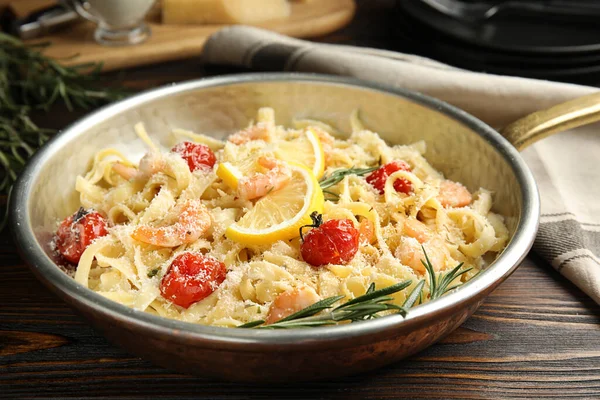 Delicious pasta with shrimps on wooden table