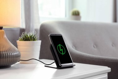 Odadaki kablosuz yayında akıllı telefon şarj ediliyor.