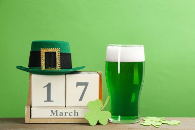 Ahşap masada yeşil bira ve yonca yapraklı kompozisyon. Aziz Patrick Günü kutlaması