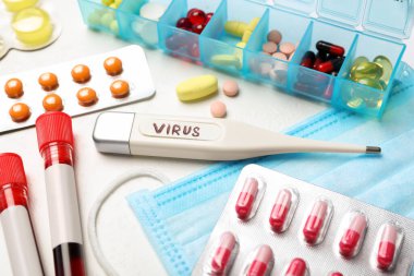 VIRUS sözcüğüyle termometre ve beyaz arka planda ilaçlar