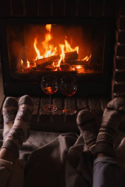 Yanan şöminenin yanında birkaç kadeh kırmızı şarap, yakın plan.