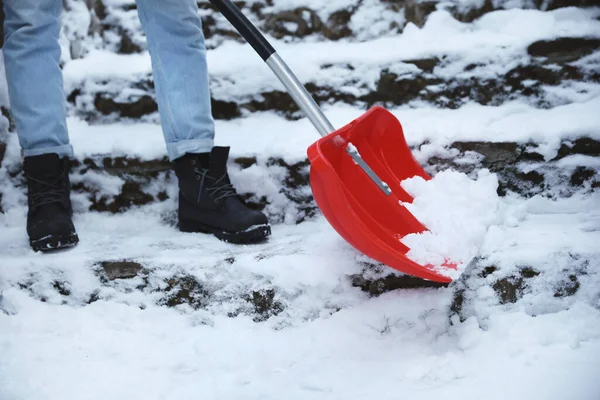 Man cleaning stairs from snow with shovel outdoors on winter day, closeup