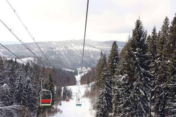 Picturesque mountain landscape with snowy forest in winter, view from ski lift