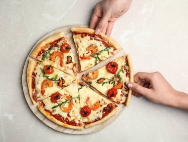 Gri mermer masada lezzetli deniz ürünleri pizzası yiyen kadınlar.