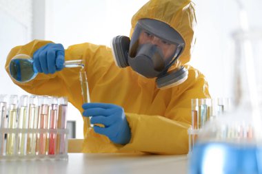 Kimyasal koruyucu giysi giyen bilim adamları laboratuardaki test tüpüne reaktör döküyorlar. Virüs araştırması
