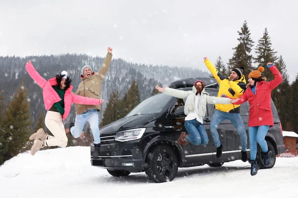 Glückliche Menschen Springen Neben Auto Auf Schneebedeckter Straße Winterurlaub — Stockfoto