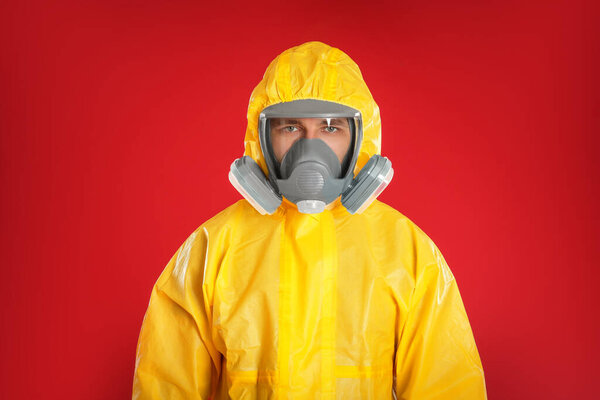 Man wearing chemical protective suit on red background. Prevention of virus spread
