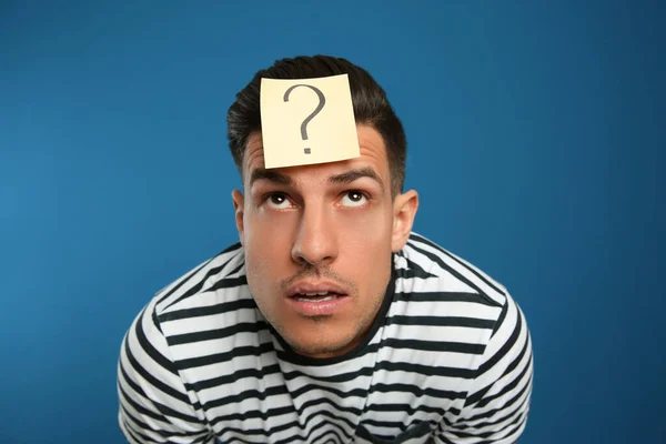 Emotionaler Mann Mit Fragezeichen Auf Der Stirn Vor Blauem Hintergrund — Stockfoto