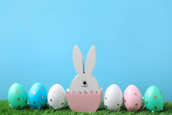 复活节兔子形象 绿色草地上的彩蛋 浅蓝色背景 — 图库照片
