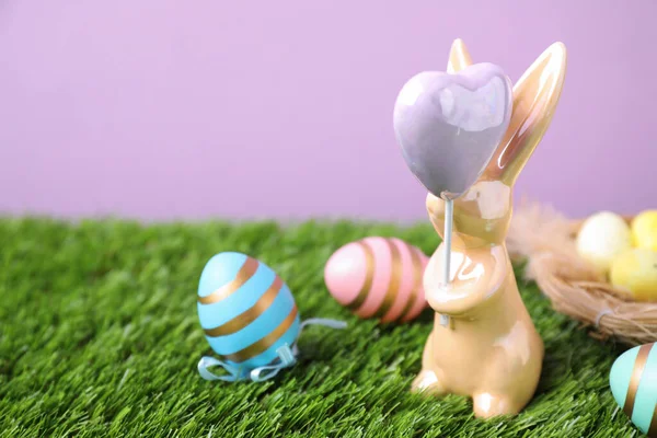 复活节兔子形象和染色蛋在绿草与紫罗兰背景 案文的篇幅 — 图库照片