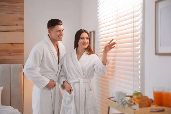 Pareja Feliz Usando Albornoces Cerca Ventana Dormitorio —  Fotos de Stock