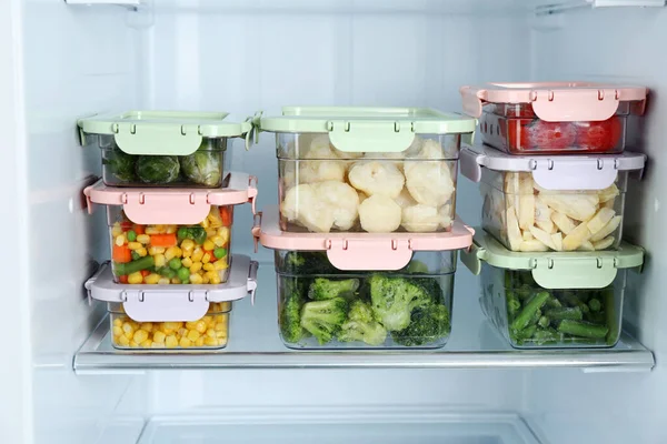 Containers with different frozen vegetables in refrigerator