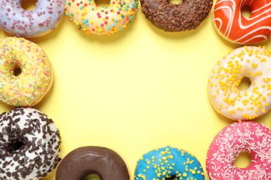 Sarı arka planda nefis jöleli donutlar, düz uzanmış. Metin için boşluk