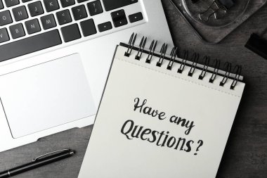 Sözcüklü defter. Gri masada herhangi bir soru işareti ve dizüstü bilgisayar var mı?