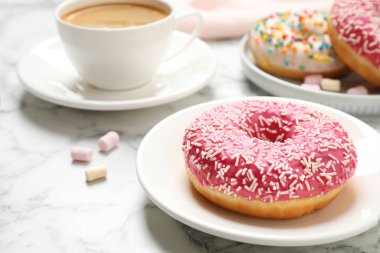 Beyaz mermer masaya serpiştirilmiş lezzetli donut ve kahve.