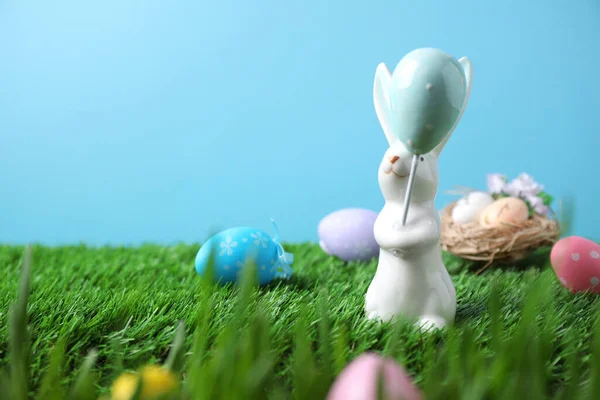 Easter bunny and painted eggs on green grass, space for text