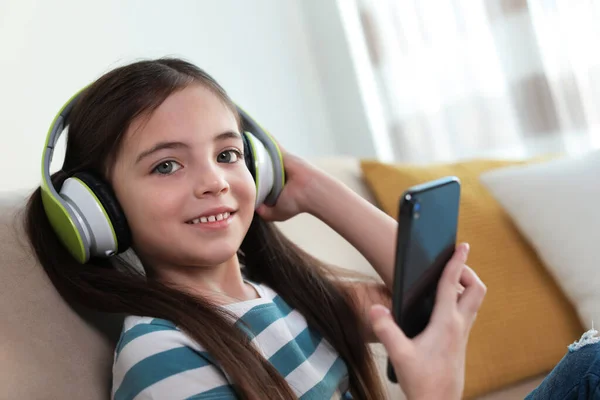 Schattig Klein Meisje Met Hoofdtelefoon Smartphone Luisteren Naar Audioboek Thuis — Stockfoto