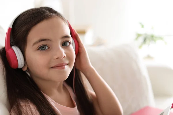 可爱的小女孩 带着耳机在家里听有声读物 — 图库照片