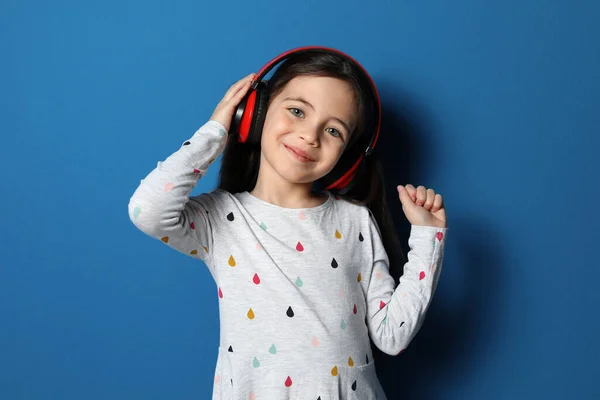 Cute Little Girl Słuchawkami Słuchając Audiobook Niebieskim Tle — Zdjęcie stockowe