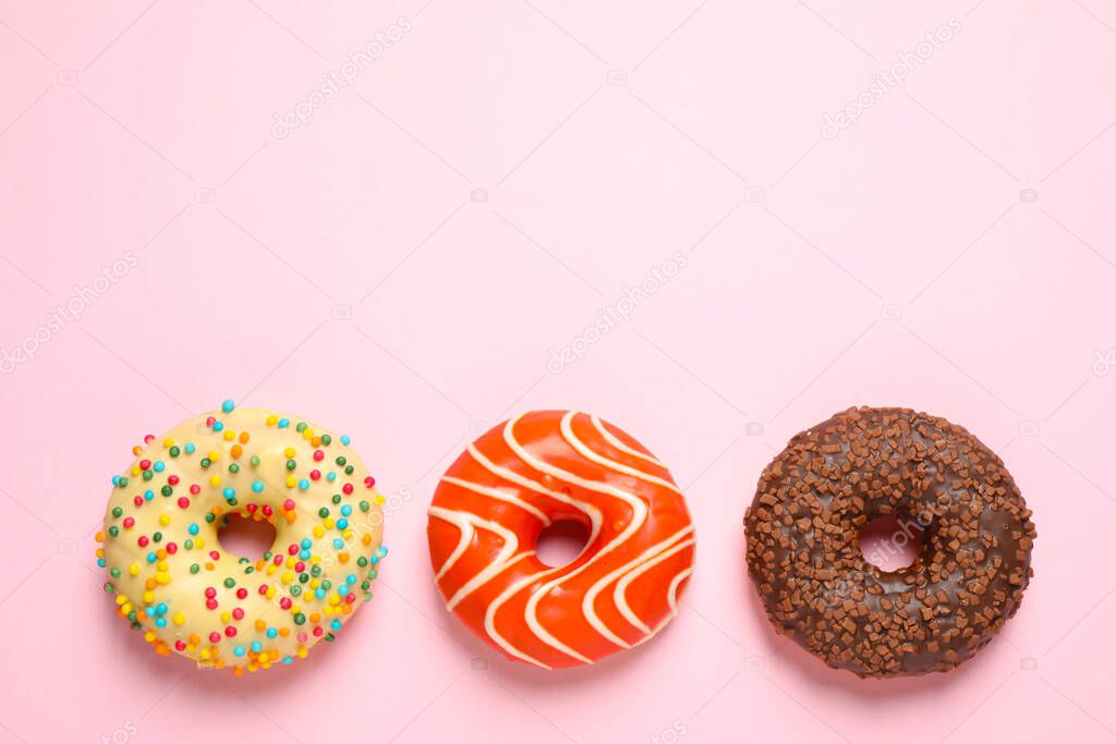 Delicious glazed donuts on pink background, flat lay. Space for text