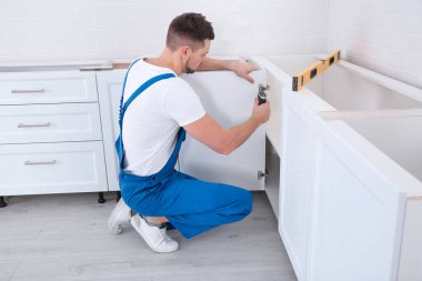 İşçi mutfağa dolap kapısı kuruyor