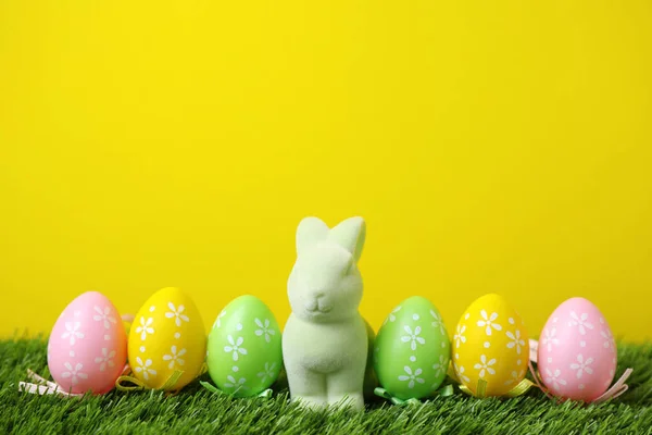 复活节兔子玩具和绿色草地上的彩蛋和黄色背景 案文的篇幅 — 图库照片