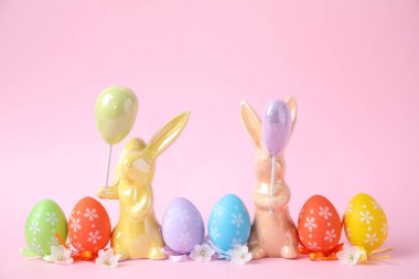 Paskalya tavşanları ve pembe arka planda boyanmış yumurtalar.