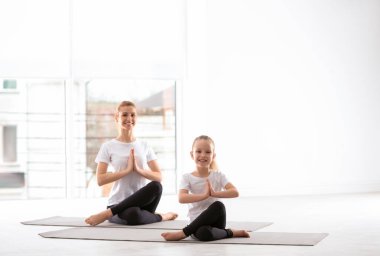 Anne ve kızı spor kıyafetleriyle evde yoga yapıyorlar.