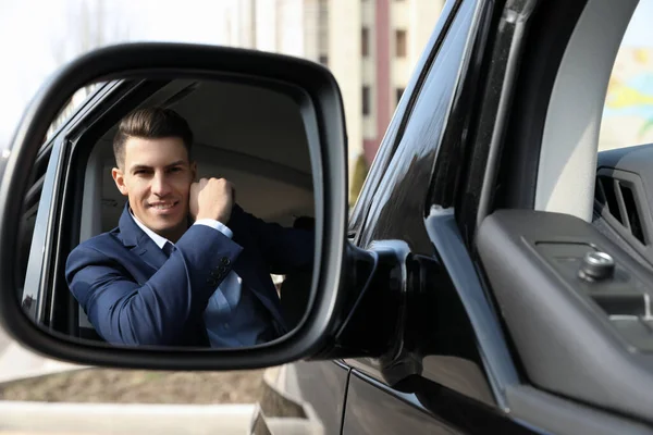 Przystojny Człowiek Patrząc Lusterko Boczne Nowoczesnego Samochodu Zewnątrz — Zdjęcie stockowe
