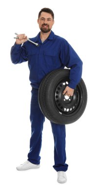 Beyaz arkaplanda ingiliz anahtarı ve tekerleği olan profesyonel oto tamircisinin tam boy portresi