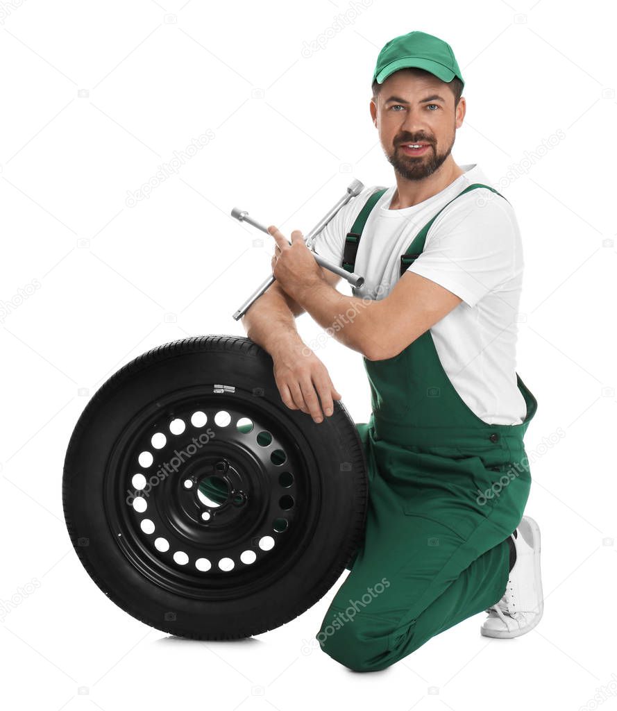 Professional auto mechanic with wheel and lug wrench on white background