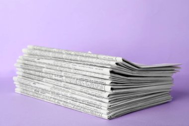 Açık mor arka planda bir yığın gazete. Gazeteci işi.