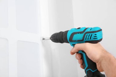 İşçi mutfak mobilyalarını elektrikli tornavidayla kuruyor.