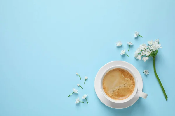 White flowers and coffee on light blue background, flat lay with space for text. Good morning