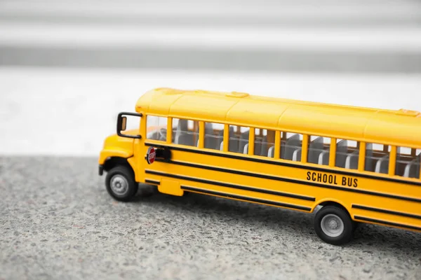 Yellow toy school bus on road outdoors. Transport for students