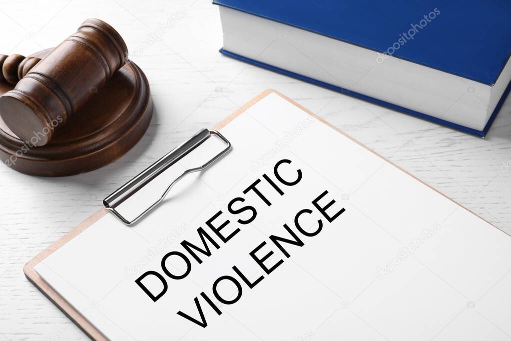 Clipboard with words DOMESTIC VIOLENCE and gavel on white wooden table, closeup