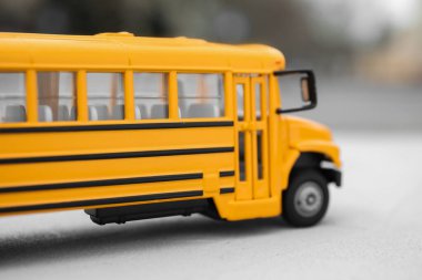 Sarı oyuncak okul otobüsü arka planda bulanık, yakın plan. Öğrenciler için taşıma