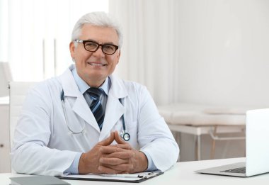 İş yerinde beyaz önlüklü kıdemli doktorun portresi.