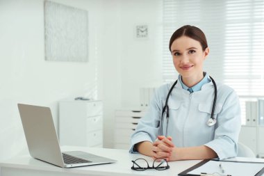 İş yerinde beyaz önlüklü genç kadın doktor portresi