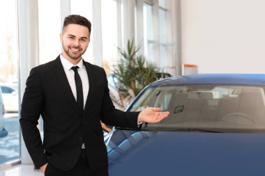 Galerideki yeni arabanın yanındaki genç satıcı.
