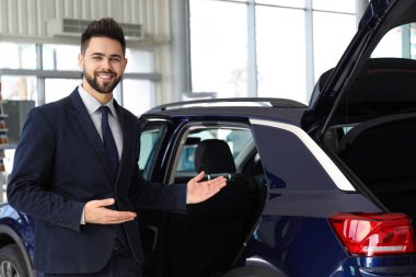 Galerideki yeni arabanın yanındaki genç satıcı.
